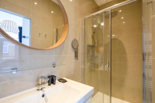 ein Bad mit einer Dusche, einem Waschbecken und einem Spiegel in der Unterkunft Charmant Appartement 1 chambre avec balcon proximité Cinquantenaire in Brüssel