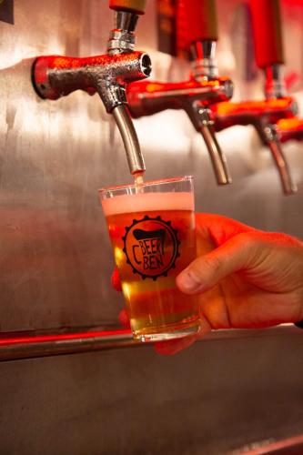a person holding a glass of beer under a faucet at CasaLina in Berbenno di Valtellina