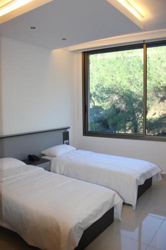 two beds in a room with a large window at Le Caravelle Beirut in Beirut