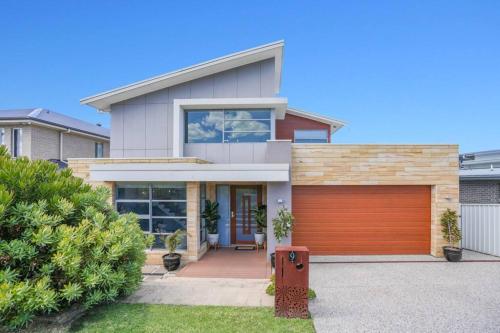 ein Haus mit einer Garage davor in der Unterkunft Modern Executive Ocean View Oasis Shell Cove Mansion 5 Minutes to Beach Sleeps 16 in Shellharbour
