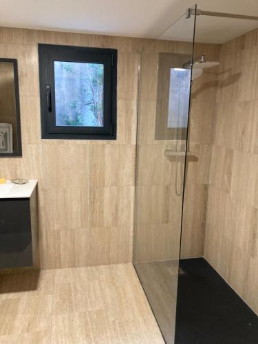 a bathroom with a glass shower with a window at Maison Milla in Saint-Égrève