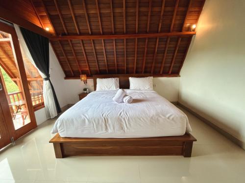 a bedroom with a white bed with a wooden ceiling at dbelish village & resto in batumadeg
