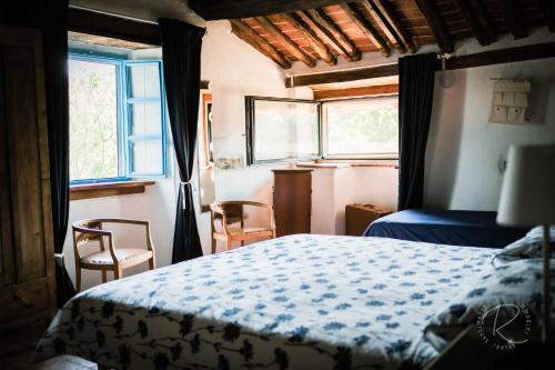 a bedroom with a bed and two chairs and a window at Cascina Boschetto in Saliceto