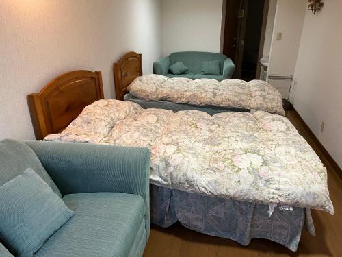 a bedroom with two beds and a couch at SkiHolic by TSH in Shinano