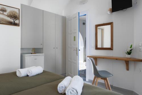 a bedroom with two beds and a chair and a mirror at KALYPSO ACCOMMODATION SIFNOS in Vathi