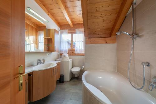 uma casa de banho com 2 lavatórios, uma banheira e um WC. em Weinberghof em Termeno