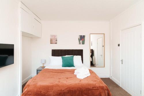 a white bedroom with a large bed with orange blanket at St Johns House in Leeds