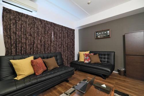 a living room with two black leather couches and a wall at 書斎でくつろぐスイートルーム in Nagoya