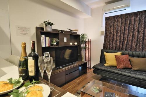 een woonkamer met een bank en een televisie bij 書斎でくつろぐスイートルーム in Nagoya