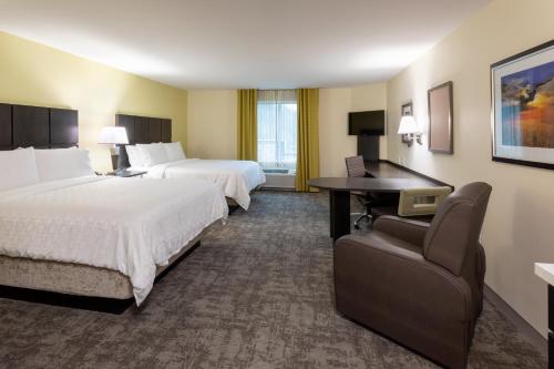 a hotel room with two beds and a desk at Candlewood Suites - Rochester Mayo Clinic Area in Rochester
