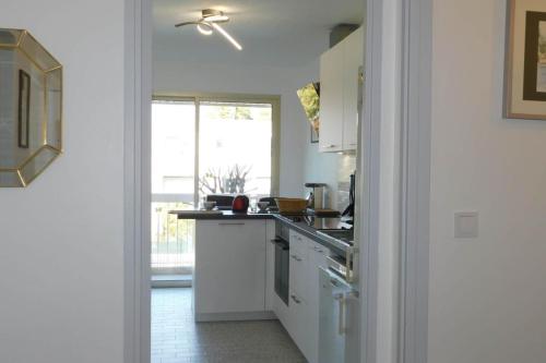 a kitchen with white cabinets and a stove top oven at Spacious T2 "Jardin du Pont du Lys" with pool and parking in Antibes