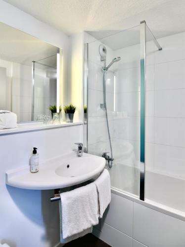 a white bathroom with a sink and a shower at ibis budget Vannes in Vannes
