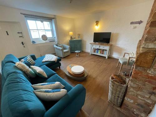 salon z niebieską kanapą i telewizorem w obiekcie Pinnacle Cottage grade II listed home at the coast w mieście Heacham