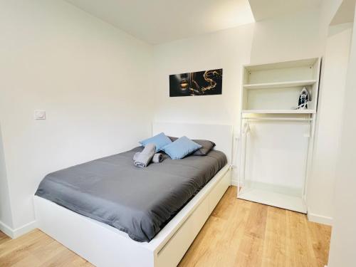 a bedroom with a bed with blue pillows on it at Le Musée 3, cocooning 2 pièces in Bergerac