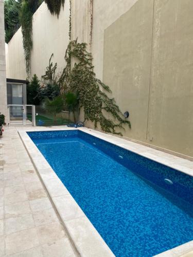 ein blauer Pool neben einem Gebäude in der Unterkunft Grand Residence apartment in Amman