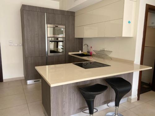 a kitchen with a counter and two bar stools at Grand Residence apartment in Amman