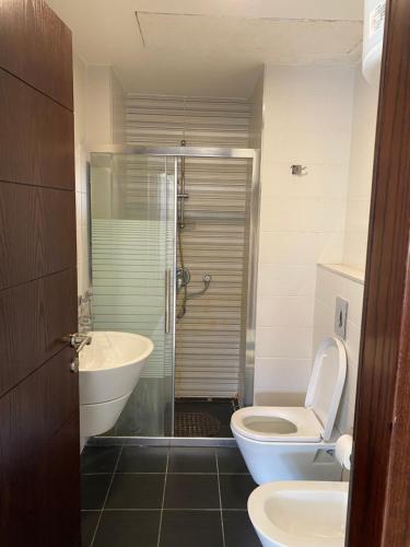ein Bad mit einer Dusche, einem WC und einem Waschbecken in der Unterkunft Grand Residence apartment in Amman