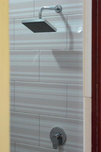 a shower with a shower head on a white wall at Maja House Penida in Nusa Penida