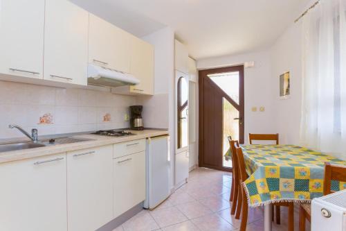 a kitchen with white cabinets and a table with a table cloth at Barbic in Medulin