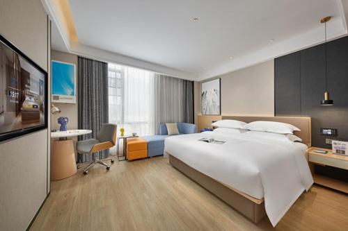 a hotel room with a large bed and a desk at Fengyue Light Shang Hotel Guangzhou Baiyun Airport Store in Guangzhou