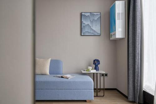 a bedroom with a blue bed and a side table at Fengyue Light Shang Hotel Guangzhou Baiyun Airport Store in Guangzhou