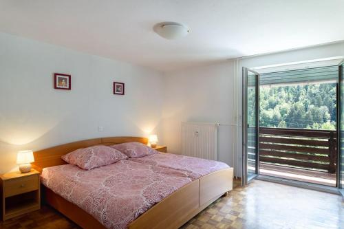 a bedroom with a bed and a large window at Iglica Apartments - First Floor in Bohinjska Bela