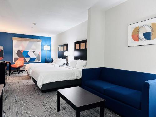 Holiday Inn Express & Suites Houston East - Baytown, an IHG Hotel في باي تاون: غرفة فندق بسرير واريكة زرقاء