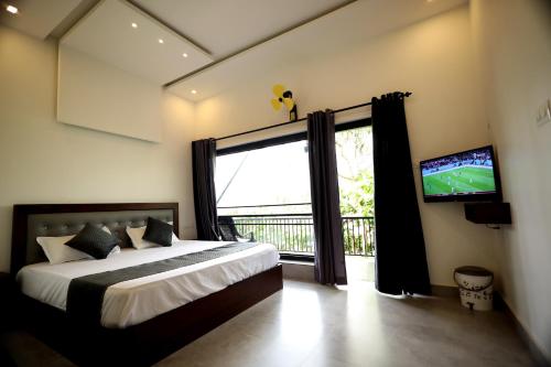 a bedroom with a bed and a tv and a window at Teaside Inns in Vythiri