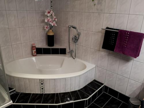 y baño alicatado con bañera y toallas púrpuras. en Tiroler Wohnung, en Arzl im Pitztal