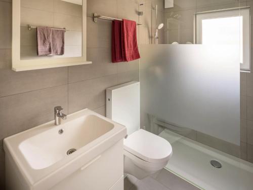 biała łazienka z umywalką i toaletą w obiekcie Chalet Soldanella w mieście Grächen