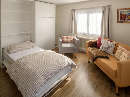 a bedroom with a bed and a couch and a chair at Chalet Soldanella in Grächen