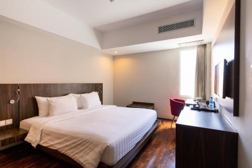 a bedroom with a bed and a desk and a television at The Bene Hotel in Kuta