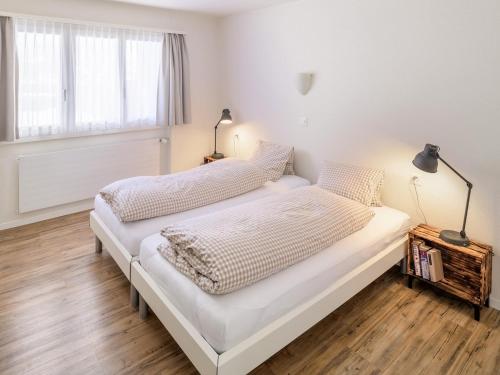 a white bedroom with two beds and a window at Chalet Soldanella in Grächen