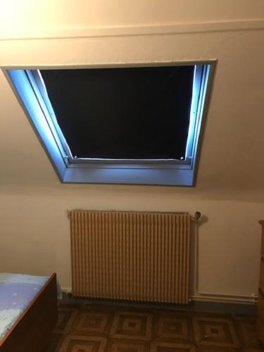 uma televisão de ecrã plano numa parede com uma janela em CHAMBRE D 'HOTE em Harnes