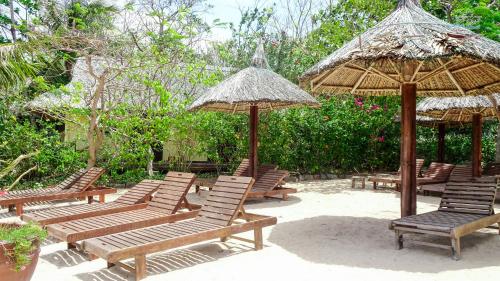 Whale Island Resort في Dam Mon: مجموعة من الكراسي والمظلات على الشاطئ