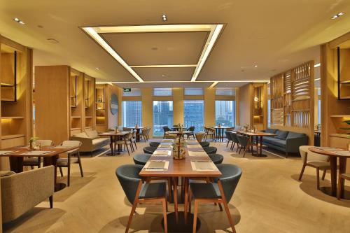 a restaurant with wooden tables and chairs andwindows at Qianyue SSAW Boutique Hotel in Hangzhou