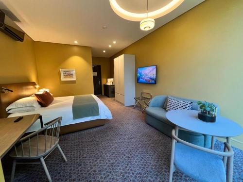 a hotel room with a bed and a table and a couch at Home Suite Hotels Rosebank in Johannesburg