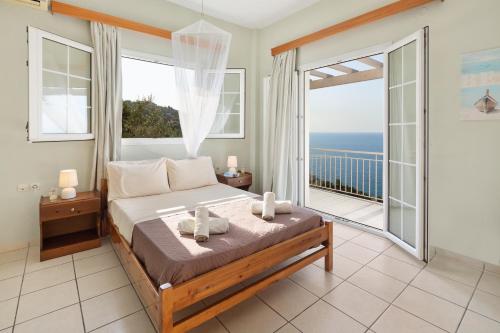 a bedroom with a bed and a balcony with the ocean at Panorama Apartments in Afionas