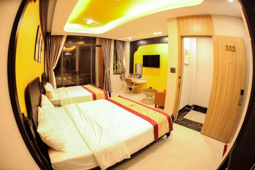 a bedroom with two beds and a room with a desk at LAHONA HOTEL in La Gi