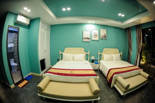 two beds in a room with green walls at LAHONA HOTEL in La Gi