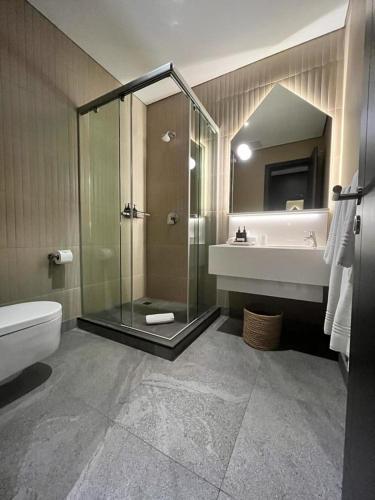 a bathroom with a shower and a toilet and a sink at Home Suite Hotels Rosebank in Johannesburg