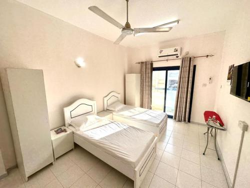 a room with two beds and a ceiling fan at Low Priced New Residential Rooms for Men Guests near DAFZA Metro Station in Dubai