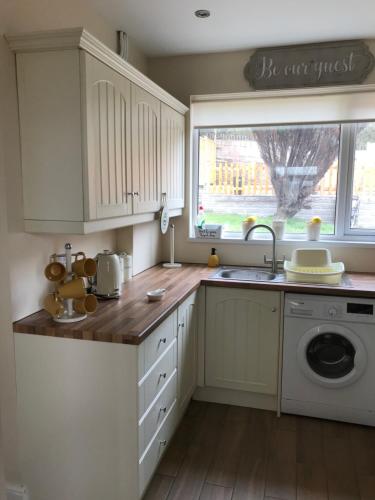 een keuken met witte kasten, een wastafel en een raam bij Mountain View Aberavon Beach, Afan Valley & Margam Park, South Wales in Port Talbot