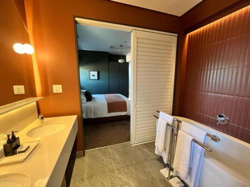 a bathroom with a tub and a sink and a mirror at Home Suite Hotels Rosebank in Johannesburg