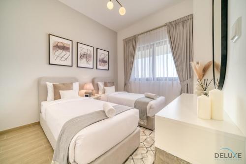 two beds in a white room with a window at Serene 2BR at The Nook Wasl Gate Jebel Ali by Deluxe Holiday Homes in Dubai