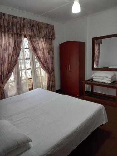 a bedroom with a large white bed and a window at Silver Rose Holiday Home in Nuwara Eliya