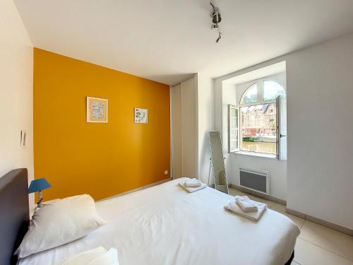 ディナンにあるAu Fil De L'Eau - Le Bord de Ranceの白いベッドとオレンジ色の壁が備わるベッドルーム1室が備わります。