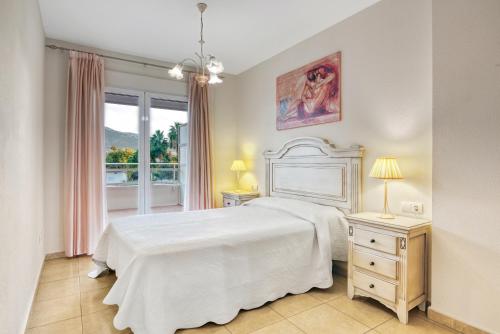1 dormitorio con cama blanca y ventana en Puerto Romano, en Denia