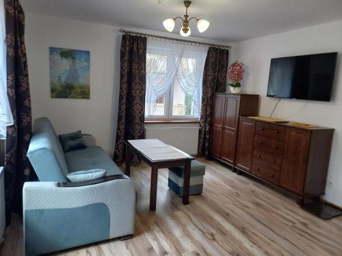a living room with a couch and a tv and a table at APARTHOTEL "Apartamenty KORONA" w Cieplicach przy basenach Termy Cieplickie koronacieplic,pl in Jelenia Góra