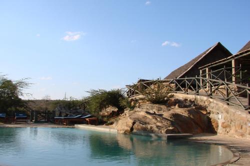 a swimming pool at a resort with a rock in the water at Maneaters in Tsavo